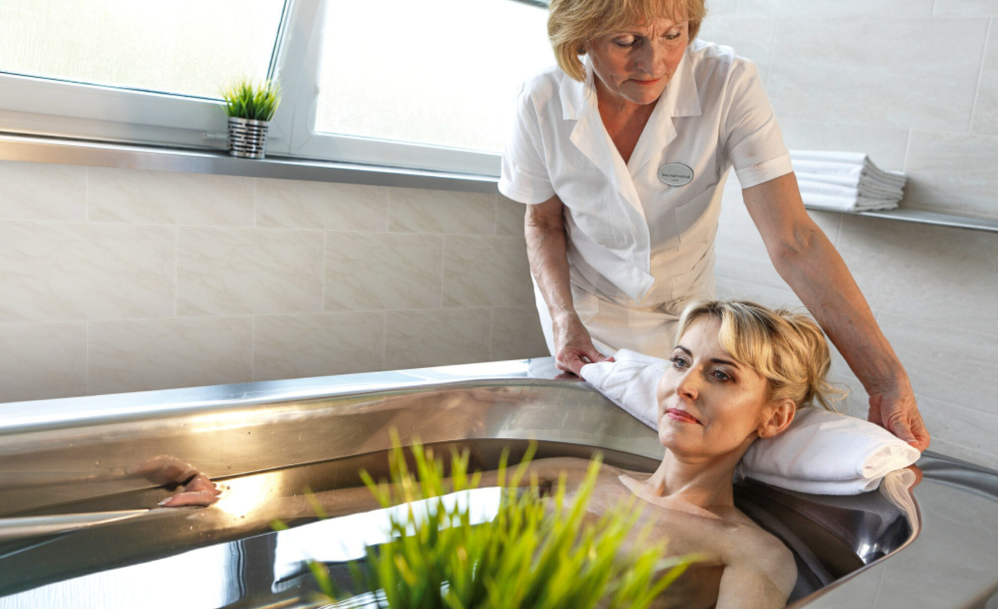 Frau nimmt ein Radonbad in einer Wanne, Therapeutin im Hintergrund